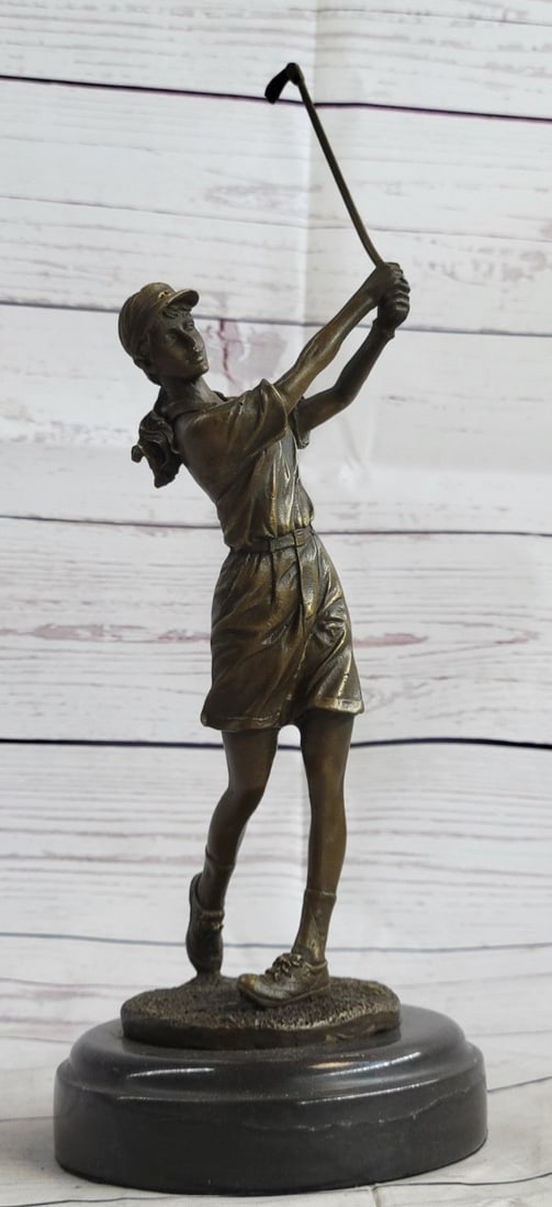 Female Golfing Bronze Sculpture: A golfer tilts her head up to the sun and watches her ball rise. She holds her form and stance, tracking the position of the ball and how close to the green it may land. Her body twists with her strok