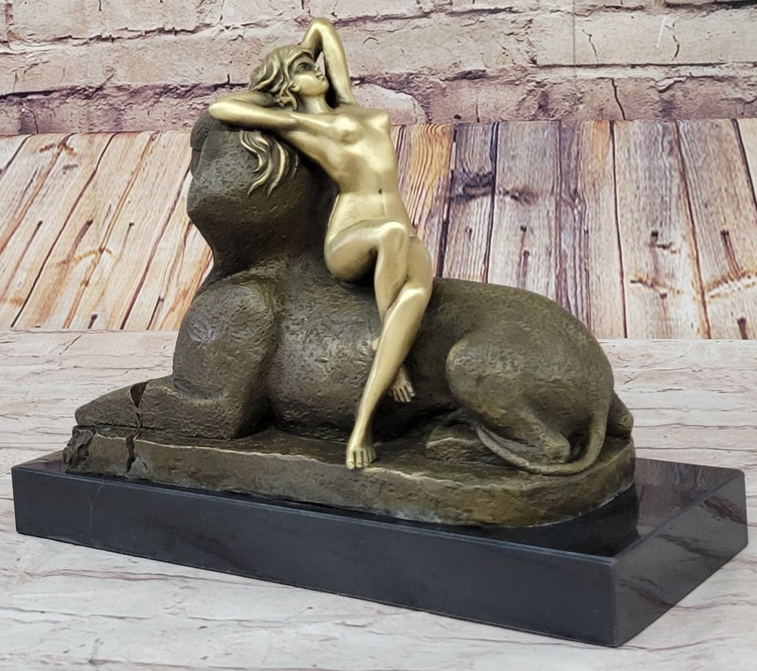 Sphinx Creature Bronze Sculpture: This exceptional French Art Nouveau figure by T. Herlinger calls upon classical influences. This stunning work captures a languid beauty lounging against a noseless Sphinx, a nod to both the neoclassi