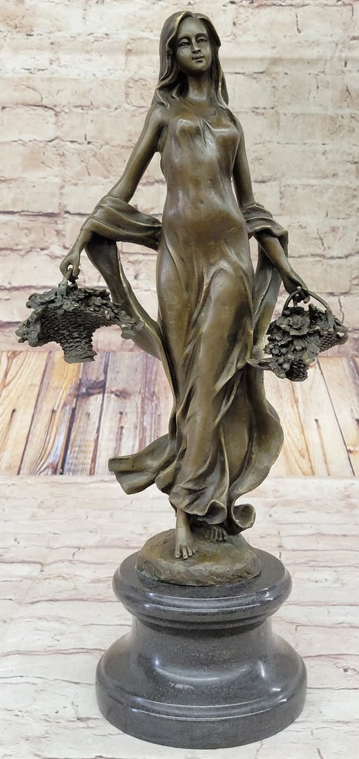 Farmer Girl with Flower Basket Bronze Sculpture: The simple and natural sculpture depicts a young woman dressed comfortably in a long loose fitted dress. The garment manages to show off her feminine body cinching at the waist and revealing her leg i