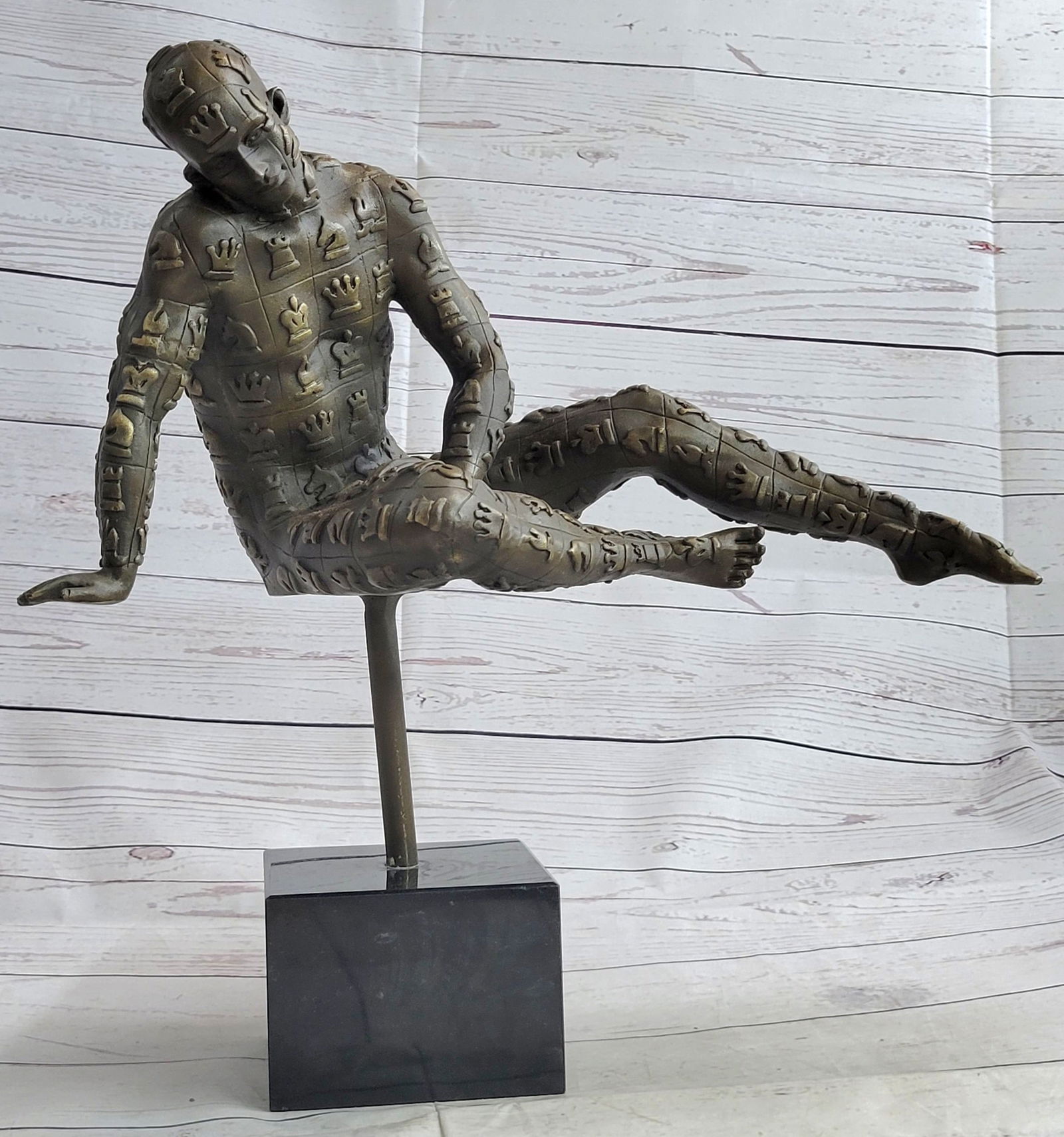Male with Chess Design Outfit Bronze Sculpture: This abstract is a very odd and creative one, I guarantee you that you will have people talking about it. You can tell it's a figure of a man suspended in the air wearing a chess design outfit, but th