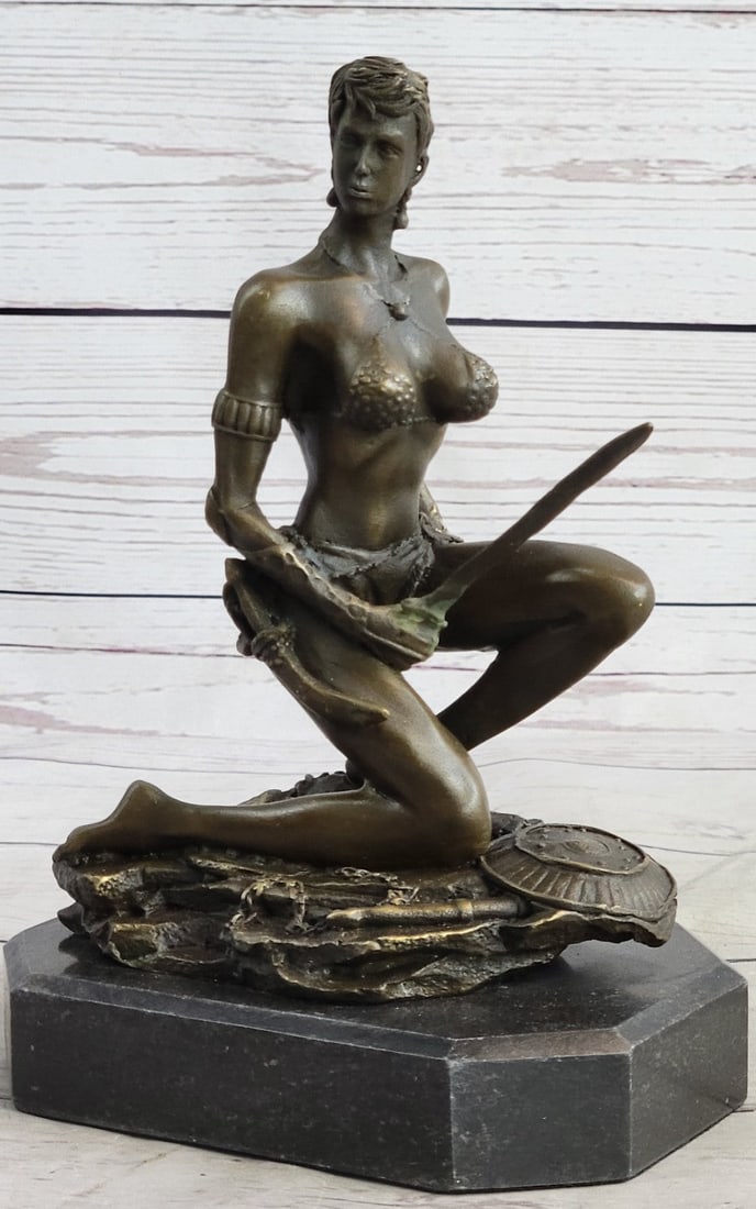 Amazon Woman With Sword Bronze Statue: A sexy and tough Amazon warrior sits proudly holding her sword. Her other arm is tense, highlighting her sculpted arms. Her large breasts are dressed in a studded bikini. She is a fighter in the wild.