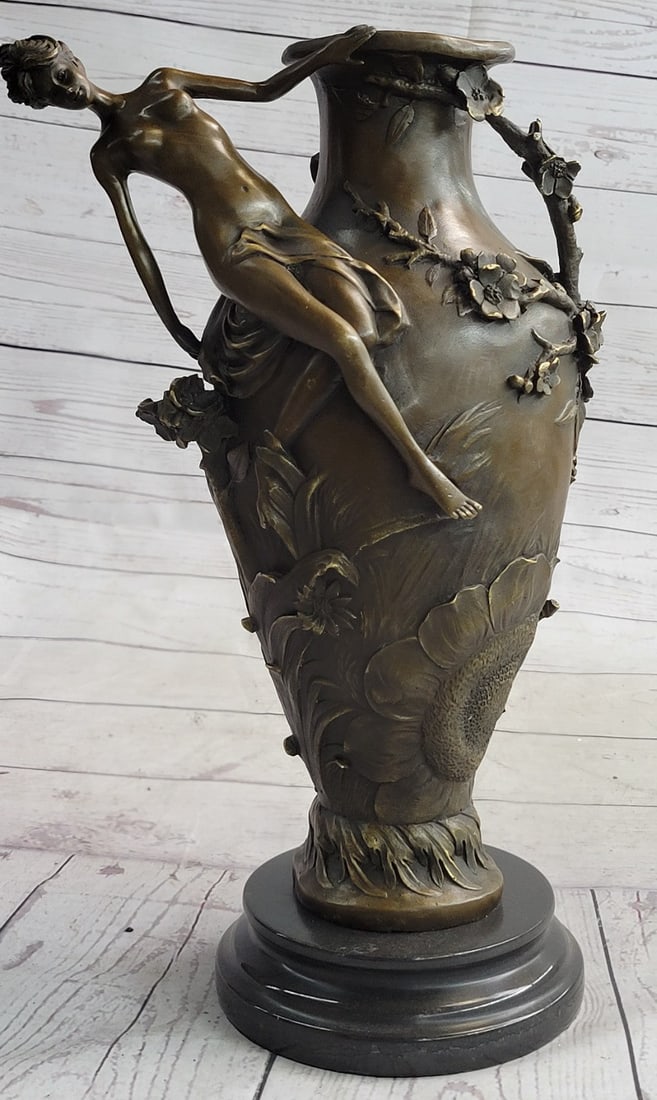 Beautiful Vase Bronze Sculpture: An exquisite vase that would be the center of attention in any room. A nude woman dangles off the edge, hovering over a field of flowers. She leans back, holding onto the edge. Vines and blossoming fl