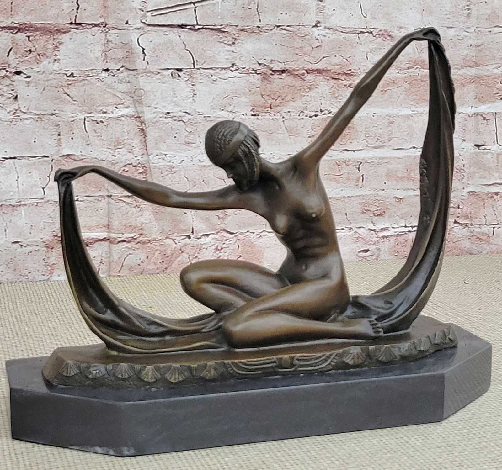 Dancer Bronze Sculpture on Marble Base: With extreme grace and expertise, this dancer strikes her beginning pose. She bows her head and holds a long yellow sash, that stretches from arm to arm. She sits on the soles of her feet, folding her