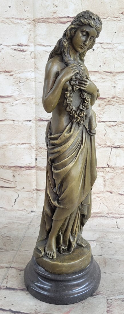 Hawaiian Hula Bronze Sculpture: The classical maiden stands in a contrapposto position, holding a rope of flowers to her chest, as the long robe slips off her gentle frame. With her eyes downcast, she gives the beholder, the emotion