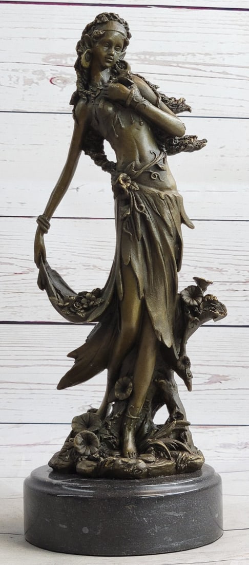 Sexy Nymph Goddess Bronze Sculpture: She holds the skirt that is wrapped in flowers and she holding a rose to her chest. She looks down upon her feet and the ground she stands barefoot in a slim-fitting dress. Her face is soft and angeli