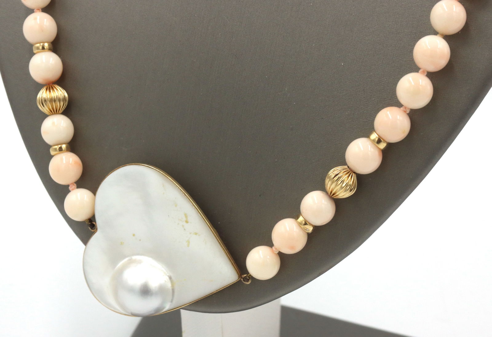 Pink quartz beaded necklace with mother of pearl heat shaped pendant: Pink quartz beaded 26-inch necklace with mother of pearl heat shaped pendant and yellow gold accents. The total weight of the necklace is 80.9 grams.
