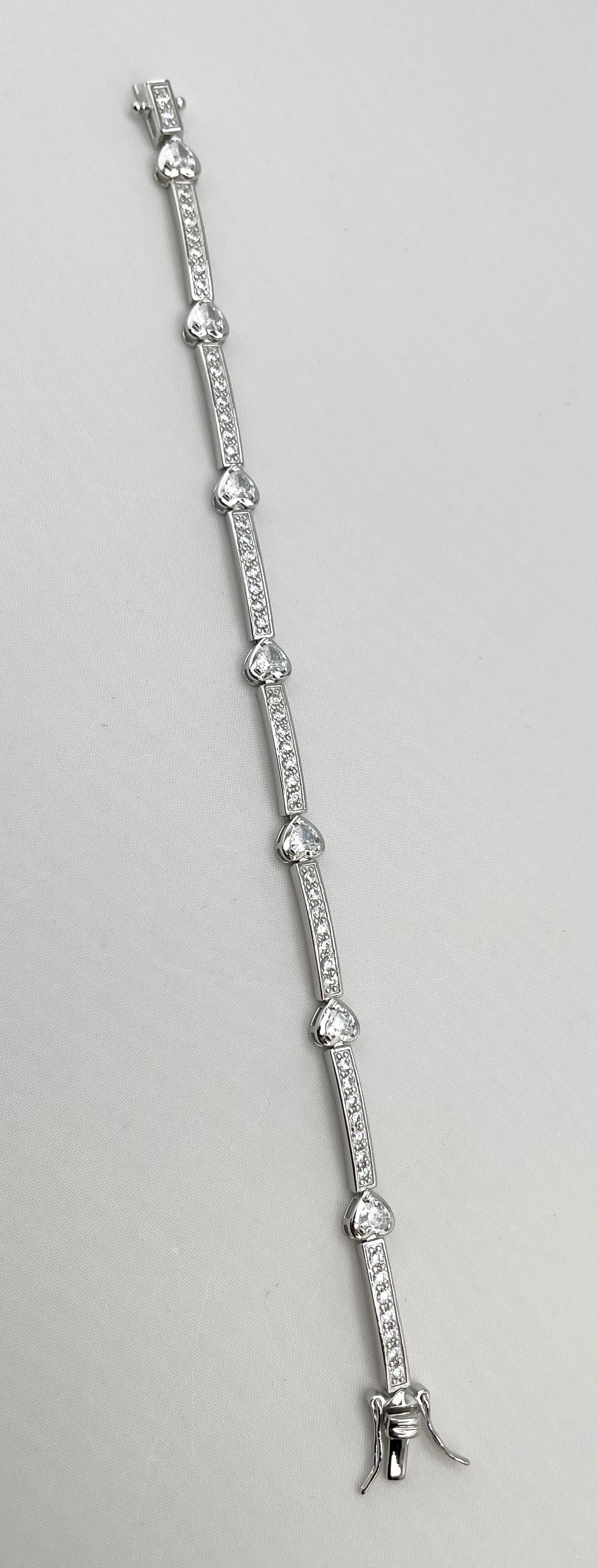 925 Sterling Silver Tennis Bracelet With Heart Station: 925 Sterling Silver CZ Tennis Bracelet With Heart Station, Has Box With Tongue And Security Lock Clasp. 11 grams. size 7.1/4