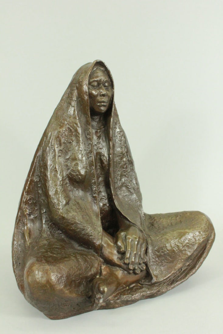 Native American Wise Elder Bronze Statue: The Native American shaman sits with the traditional Indian legcross on the ground of the earth. The long cloak covers him like a mysterious veil revealing his peaceful face that is lost in transition