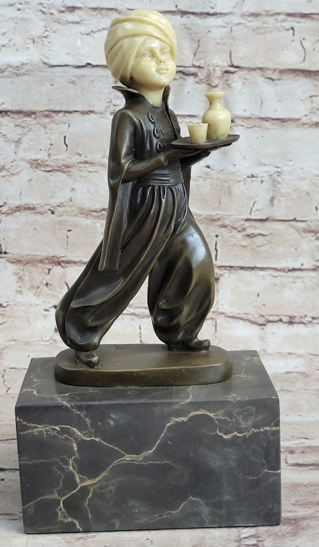 Amazing Little Indian Boy Server Bronze-Bone Sculpture: This amazing little Indian boy looks to his right as he walks a plate of a water pitch and a little cup. He wears a turban on his head as the tradition requires. He wears this gypsy type of pants and 