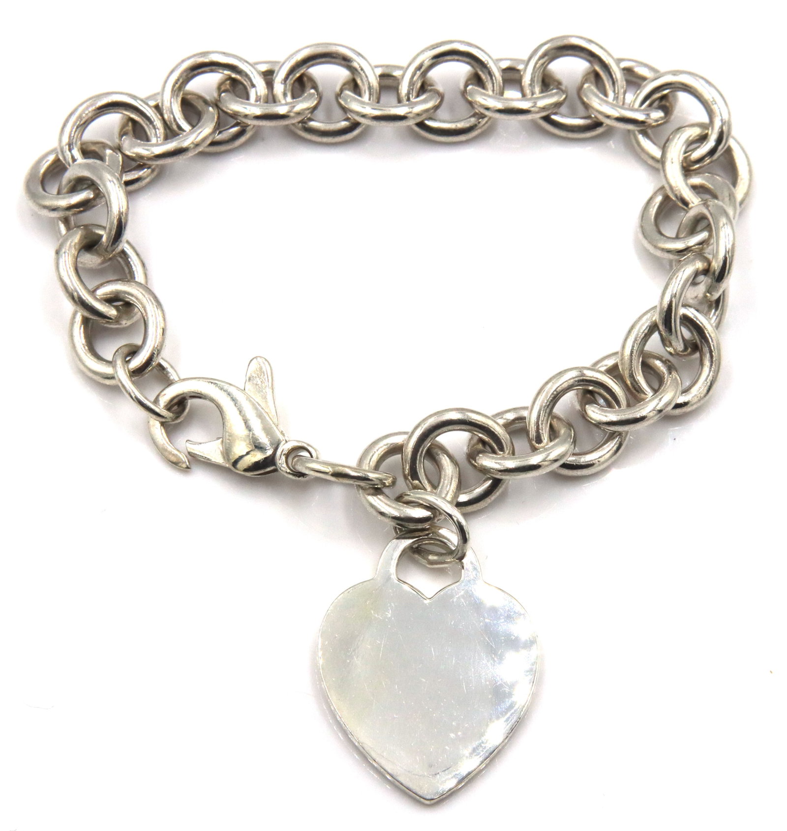 Tiffany & Co link bracelet with heart shaped charm: 925 Sterling silver Tiffany & Co 7-inch link bracelet with heart shaped charm. The total weight of the bracelet is 35 grams.