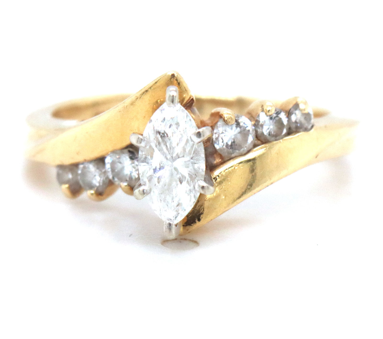 14kt Yellow gold marquise diamond ring: 14kt Yellow gold marquise diamond ring with round brilliant cut diamond accents. The total weight of the ring is 3.2 grams. Ring size 4.5".