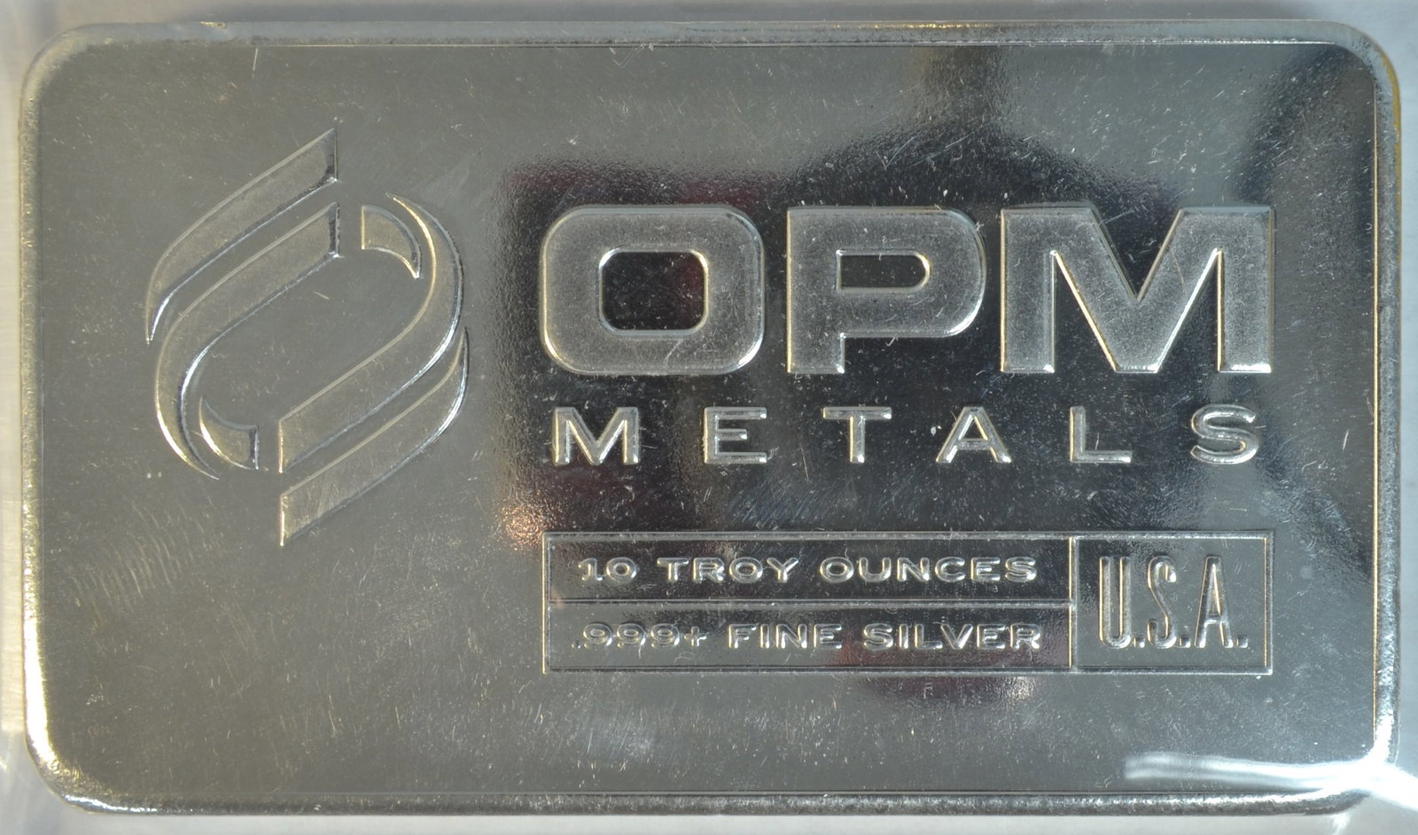 OPM Metals 10 oz .999 Fine Silver Bar Sealed in Plastic: OPM Metals 10 Troy Ounce Silver Bar, struck in .999 fine silver. Produced by OPM Metals, this bar contains 10 ounces of pure silver and comes sealed in protective plastic to help preserve its conditio