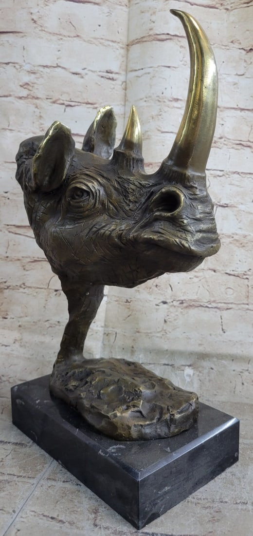Rhino with Horn Bronze Sculpture: The horn of a rhinoceros is the animal's unique and defining physical characteristic other than its massive size. This piece is of a rhinoceros head yet it fully depicts the animal's ill temper and st