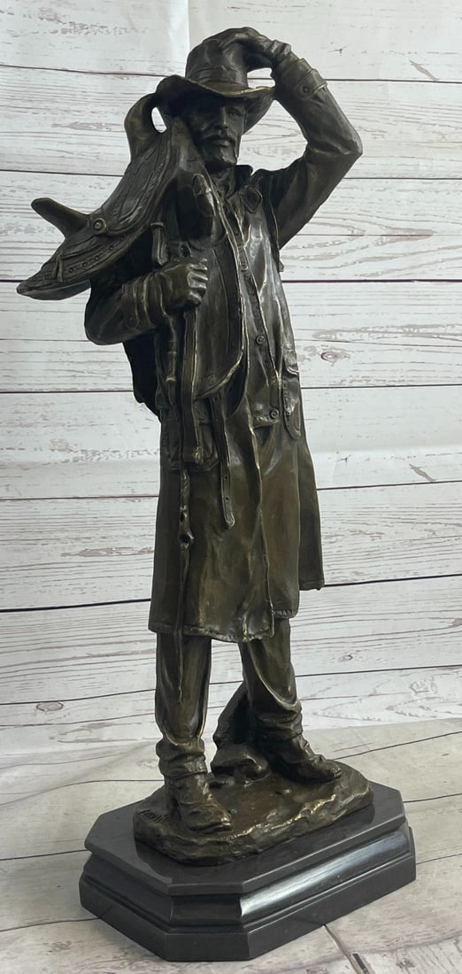 Western Cowboy Bronze Sculpture: This is a Sculpture of a classic cowboy. He wears his cowboy hat and his trench coat. On his feet, he wears boots that his jeans cover in between his legs is a bunch of twigs that were gathered for th