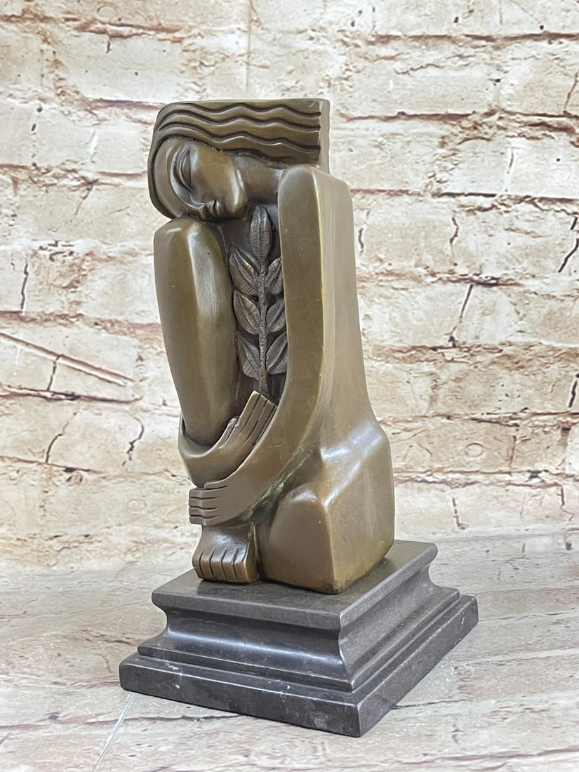 Woman Bronze Figurine: An abstract Sculpture of a woman seated on the bent knee with her head resting on one knee. In the center is a long stem of leaves. The lines on the leaves are in opposition to the wavy lines sculpted