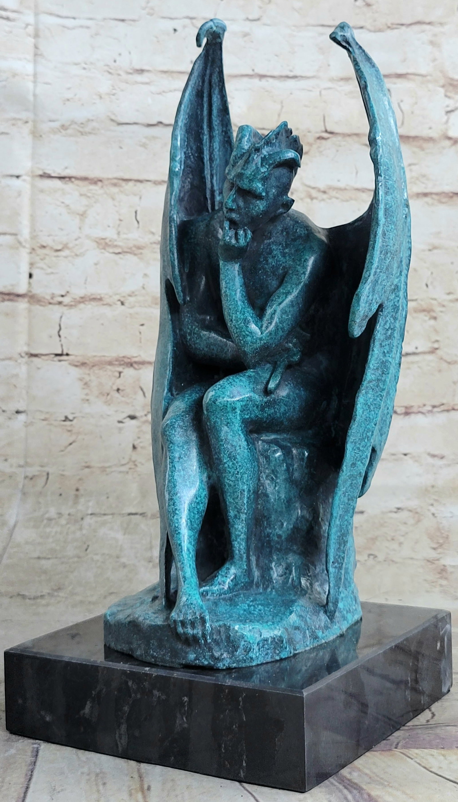 Green Patina Devil Bronze Sculpture: He wraps himself in his wings and holds onto a crucifix while sitting and thinking about his presence in the world. This gargoyle devil has the body of a man but the fingers and toes of a gargoyle.