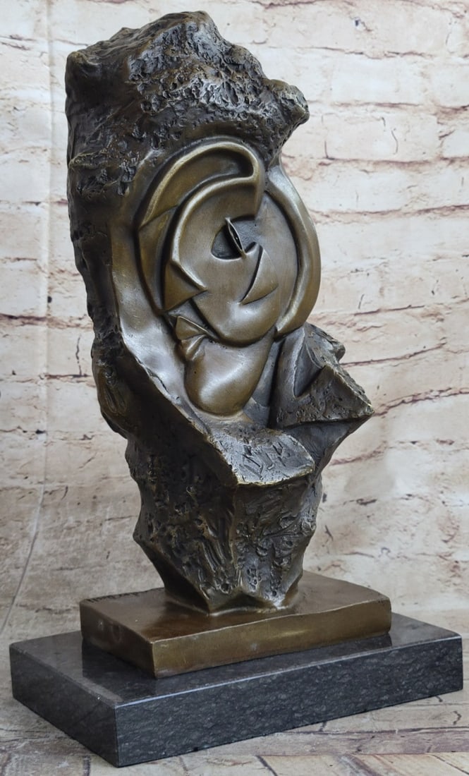 Modern Art Face Carved on Rock Bronze Sculpture: This abstract sculpture is a great conversation piece. There is a profile of a person that is smoothly carved onto a stone rock. The contradicting style of the smooth, abstract profile and rough