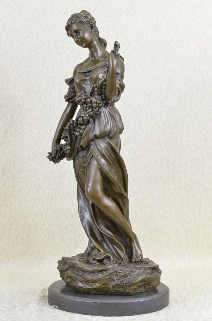 Young Woman with a Long Stem of Fruit Bronze Statue: The simple and natural sculpture depicts a young woman dressed comfortably in a long loose-fitted dress. The garment manages to show off her feminine body cinching at the waist and revealing her leg i
