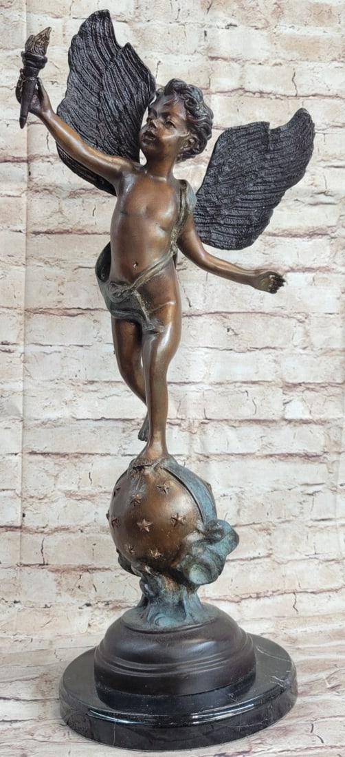 Angel Cupid with Torch of Victory Bronze Sculpture: Mounted on a rounded golden ball designed with green around it, stands a young cherub drawing his bow, ready to shoot his arrow of love. An over-sized feather lies around his waist slightly covering h