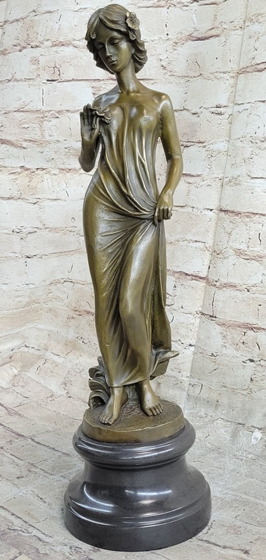 Young lady Gazes into a Flower Bronze Sculpture: The young lady gazes into a flower. The look in her eyes hints that it might be a gift from an admirer. She is dressed in a simple long gown that clings to her figure. She clutches the fabric with her