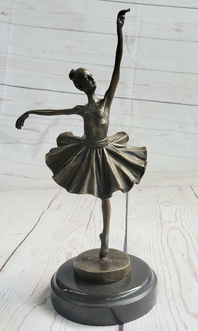 Graceful Ballerina Bronze Statue: A prima ballerina puts on a show. Well trained in the art that she loves, she shows off her agility, balance, and flexibility. She elevates her long leg far behind her. Her chest pushes out and her he
