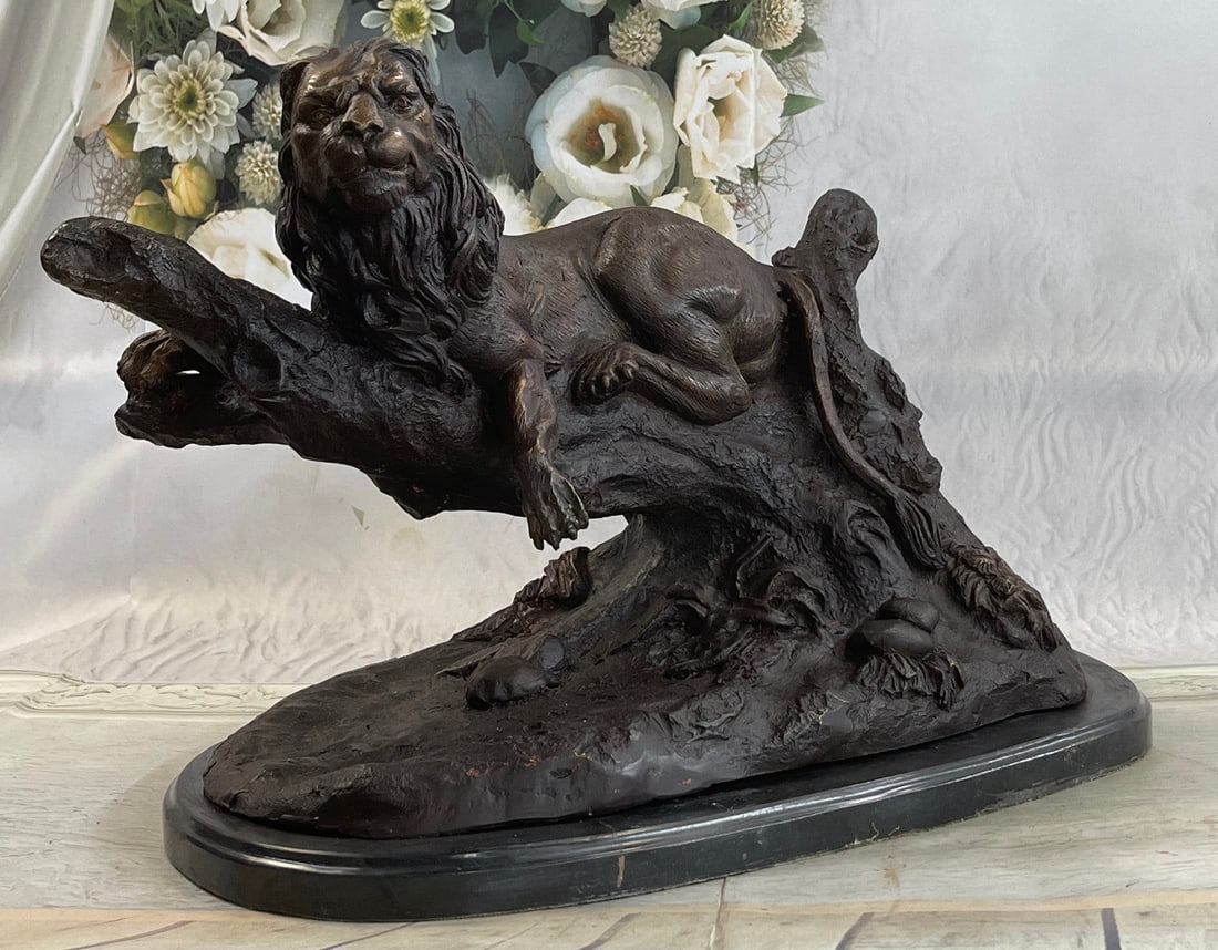 Lion Resting Bronze Sculpture: A ferocious lion bears his strong lean muscles while resting on a tree stub. He has a thick, wavy mane that falls on his chests and back. In his eyes is an intensity that can only mean a fight lies ah