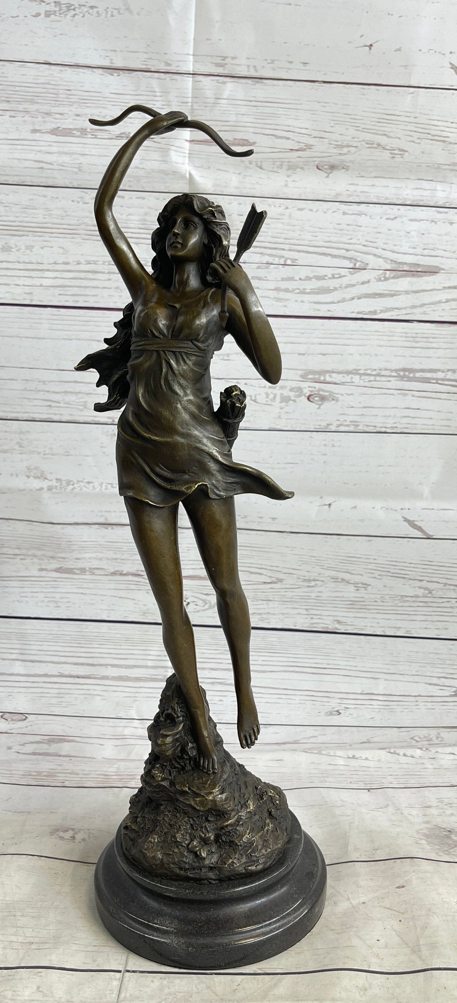 Diane The Hunter Bronze Sculpture: This curvaceous beauty runs away with his bow and sack of arrows. She holds an arrow in one hand and holds up the coveted bow in the other. This brown patina sculpture was cast using the Lost Wax