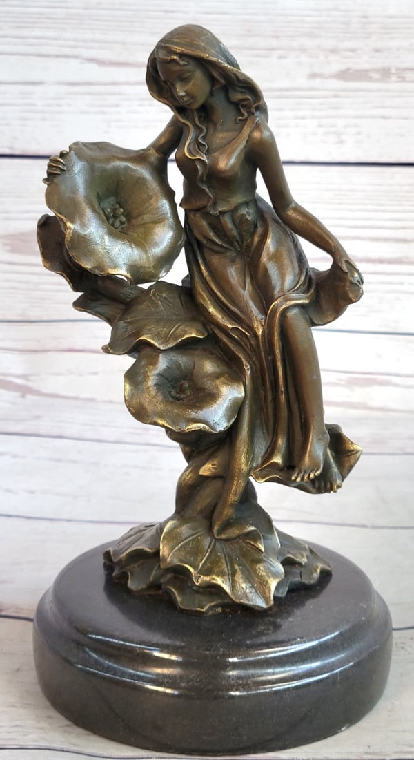 Daydream Girl Bronze Sculpture: Get lost in a daydream. She leans back on a tree stump and flowers grow all around her. She stretches an arm out to feel the blossom graze her skin. She is one with them as they curve around her. Her 