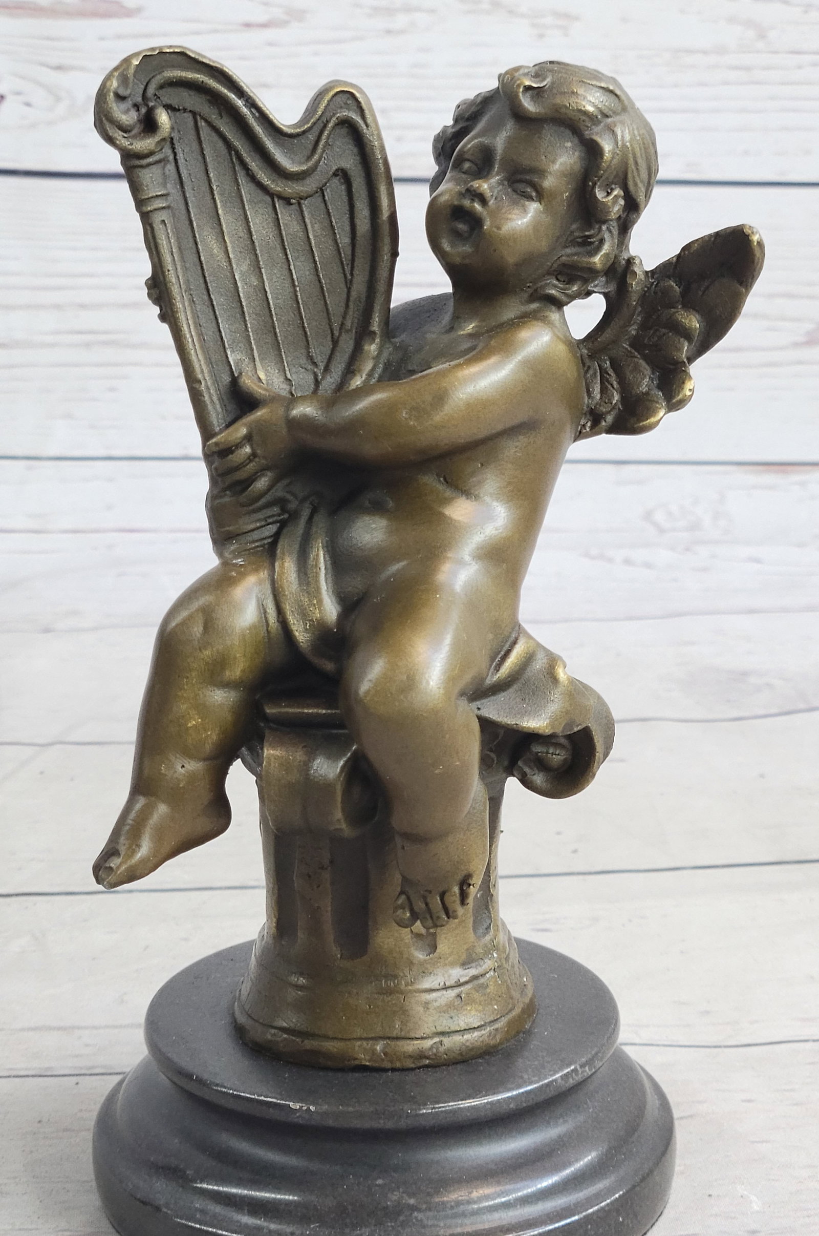 Angel Music Genesis Cherubs Harp Bronze Figurine: This beautiful Bronze Statue depicts an adorable little cherub playing the Harp. It is part of a series of cherub musicians and would look equally good inside your house or in your garden. He has a