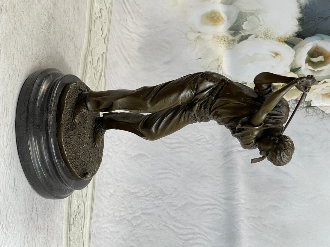 Golfer Bronze Statue: A golfer tilts her head up to the sun and watches her ball rise. She holds her form and stance, tracking the position of the ball and how close to the green it may land. Her body twists with her strok