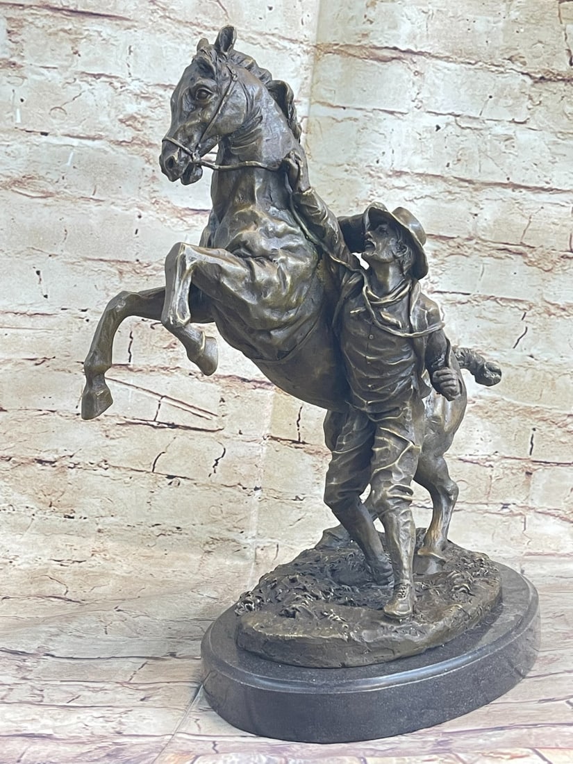Man With Horse Bronze Sculpture: The Western cowboy grabs the reins on his horse. The excited horse rears in a heated moment, lifting its front legs in the air. The brave cowboy is attempting to calm this horse from his excited state