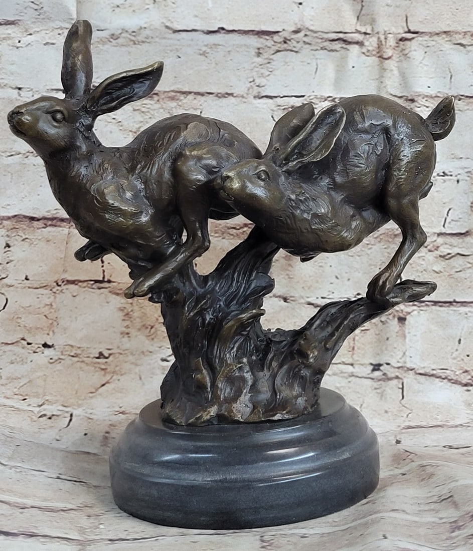 Two Running Hare Bronze Figurine: This sculpture was cast using the Lost Wax Method and has a two-tone brown patina and is mounted on a marble base. Dimensions: Height 10 X Width 9 inches. Weight: 9 LBS.