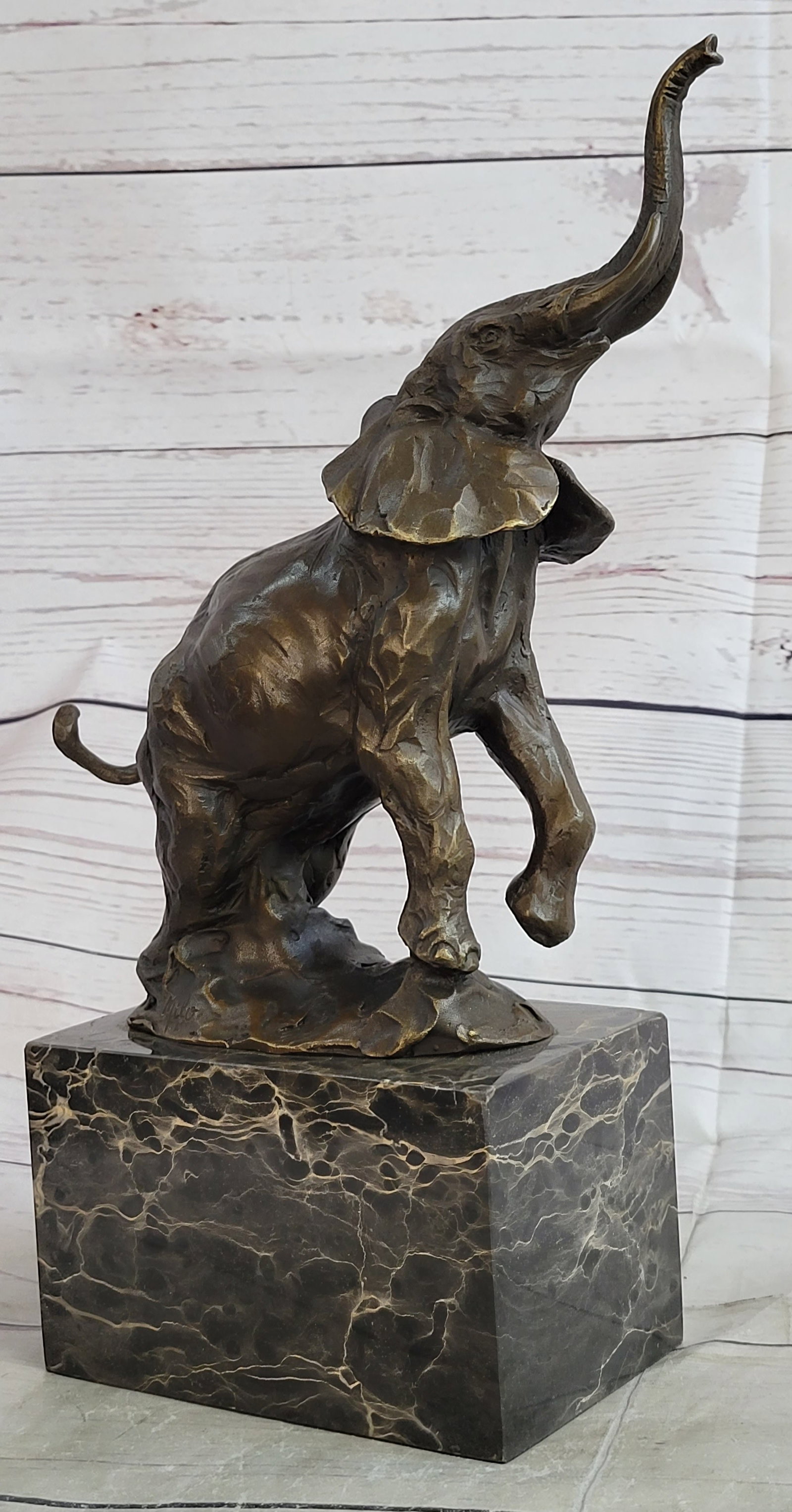 African Elephant Bronze Statue: The elephant can be envisioned tracking slowly and majestically across the ceaseless dryness of a plain in search of a watering hole or the shade of trees. He pulls his trunk outward as he passes on