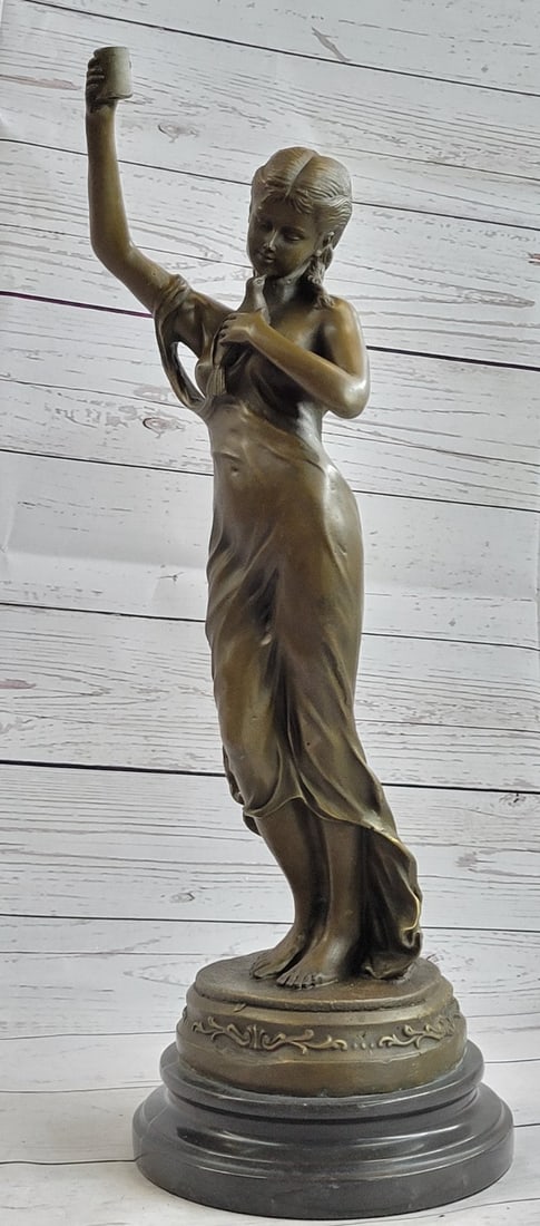 Young Lady Cautiously Posing Bronze Sculpture: After a long hard day in the garden, a young girl makes her way home. With her cup of drink in one hand and a little bird in her other hand, she shares a slight smile and a worn look. Her dress is