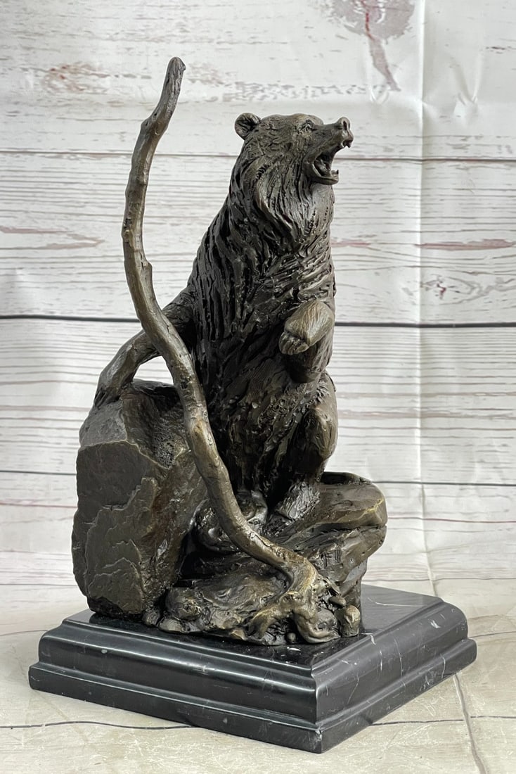 Bear Standing on Cliff Bronze Sculpture: It features a bear standing on top of a cliff leaning its weight into a rock with a large branch in front of it. As the bear stands on its hind legs, it reaches the height of the nearby branch