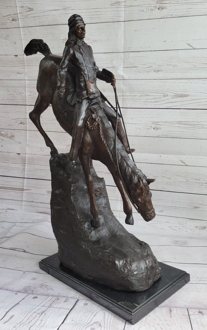 Mountain Man Bronze Sculpture: A lone cowboy sets out on a long journey. His loyal horse slowly descends a slanted mountain. His long legs navigate the rough terrain carefully. The cowboy sits tall and clutches the reins. This two-