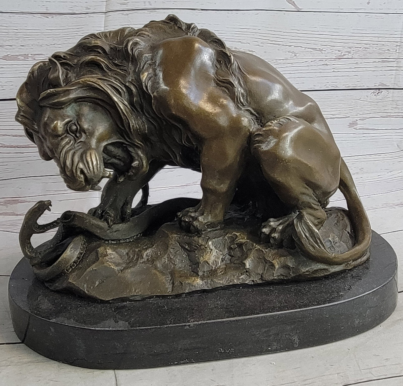 Lion and Snake Bronze Sculpture: This is a beautifully sculpted piece of a Lion and a serpent in stand-off . The majestic male Lion, irritated by the hissing venomous threats of the Snake, bends down, cowering over the coiling snake,