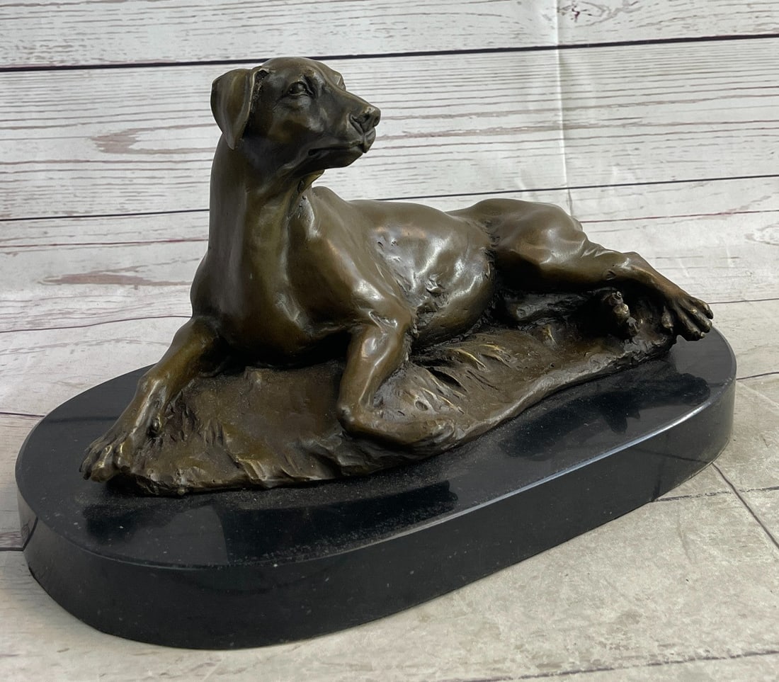 Dog Bronze Sculpture: This gracious dog lays down and soaks in the weather. He looks up at the sky ever so peacefully and he waits for his owner. Like a man's best friend he is the most reliable and honest best man. The