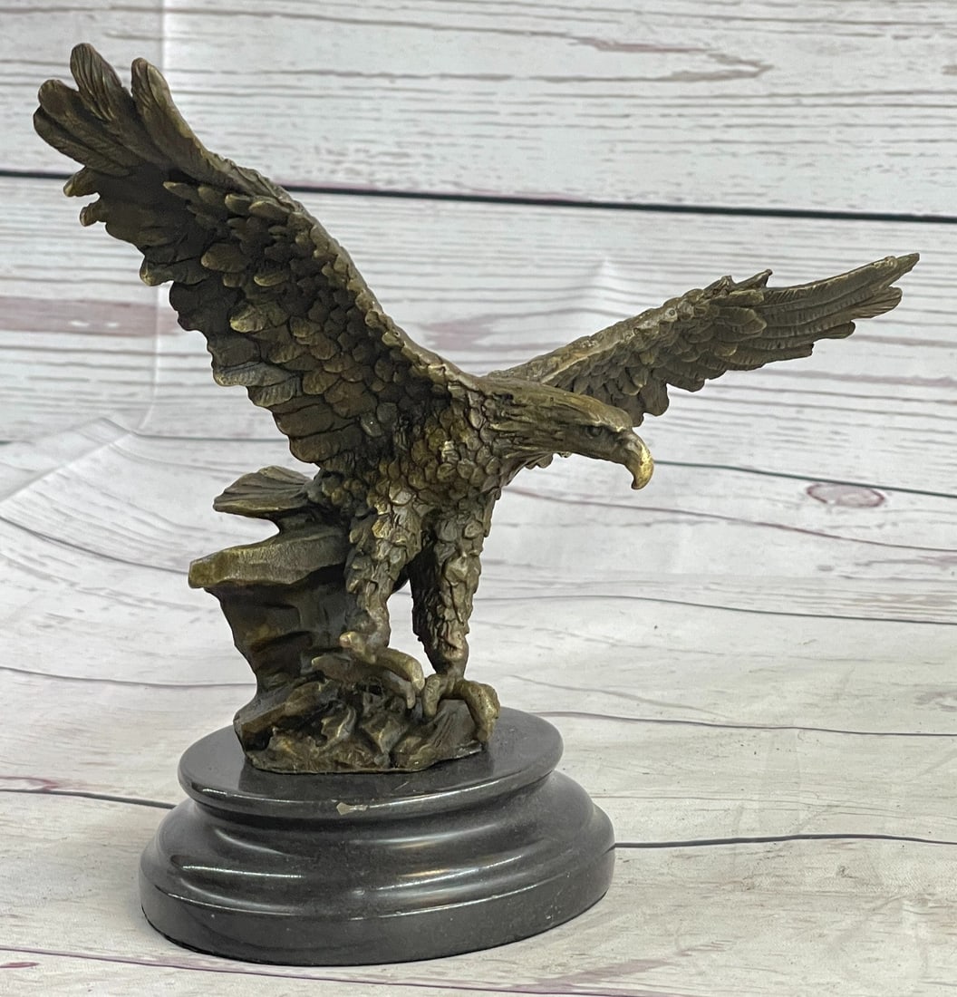 Eagle Bronze Sculpture: A small eagle descends and is preparing to land down. His clawed feet spread ready to grip onto the landing. The eagle's expansive wings, designed with exquisite detail, flap high in the sky as it is