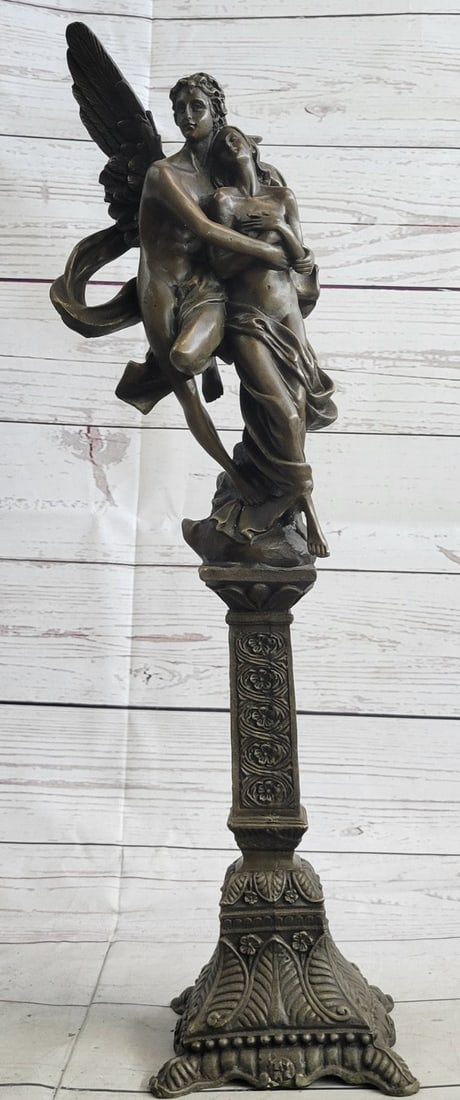 Eros and Psyche Mythical Bronze Figurine: A nude male angel carries a nude girl and in his arms. The girl clutches her bare chest as her head tilts up to her lover and protector. They are almost nude with only a cloth lightly draped over the