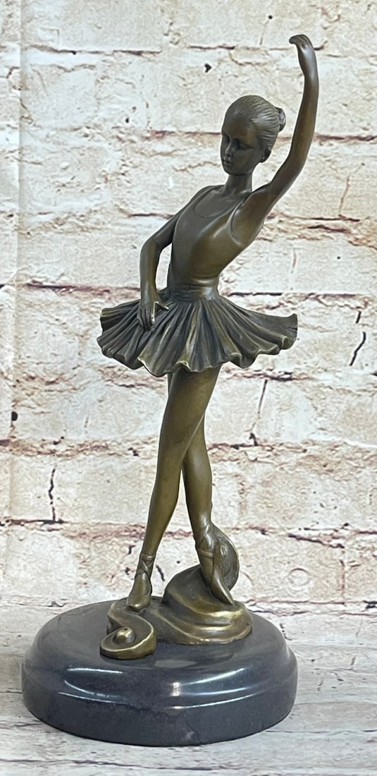 Ballerina Ballet Bronze Sculpture: The young and beautiful ballerina stands tall and graceful with her eyes lowered and a nice smile on her face. She wears a tutu and ballet shoes that tie around her ankles like the classic costume of 