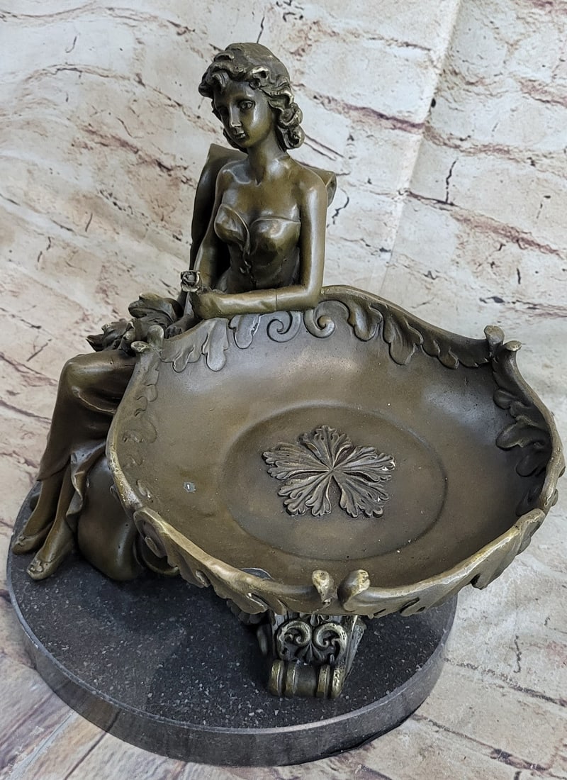 Business Card Holder Bronze Sculpture: This decorative sculpture is one that will surely fascinate and delight. A young girl rests with a large stylish plate placed on her lap. She is half-nude with her skirt flowing back behind her. The p