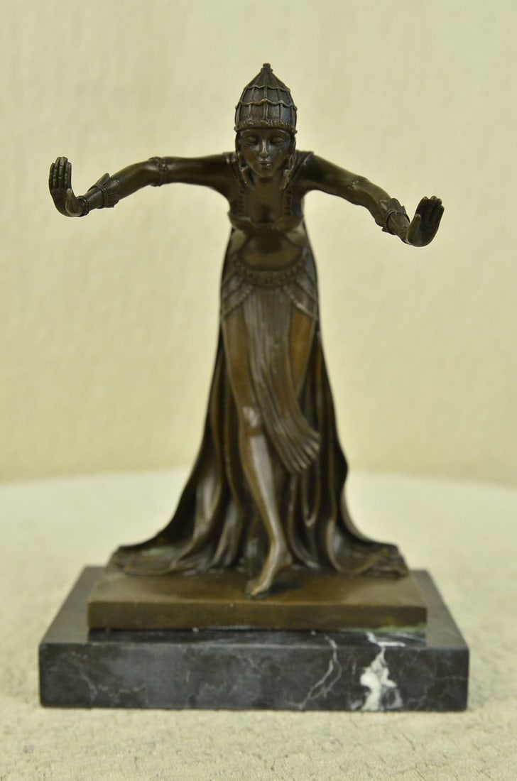 Dancer Bronze Sculpture: This Egyptian princess bows graciously with her hands out to her side as her long royal flowing dress cascades down her legs and gathers at her feet. On her head she wears a jeweled crown that has fla