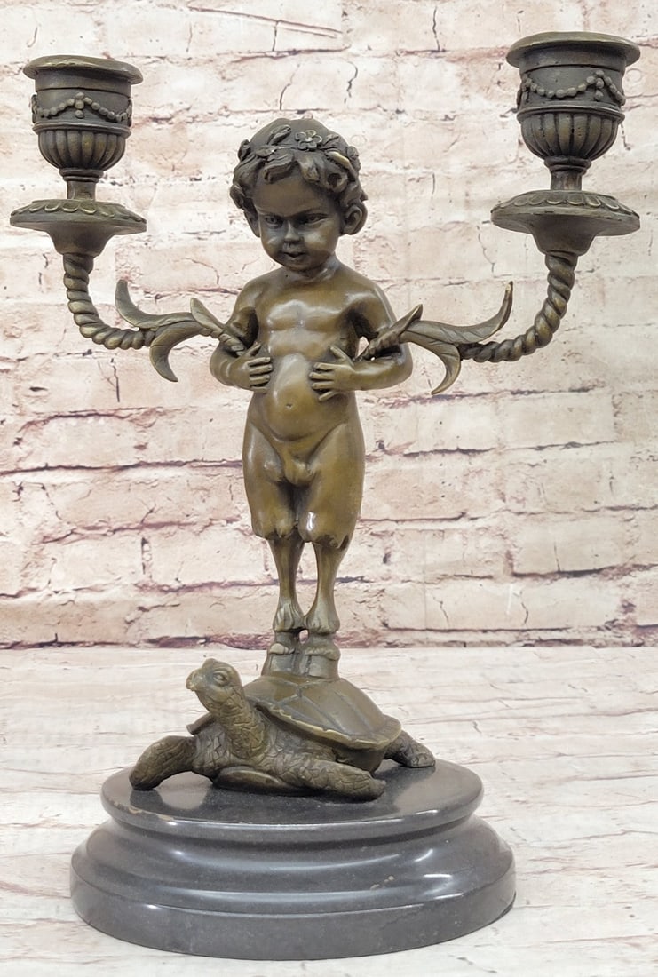 Candle Holder Bronze Statue: Candelabrum is held underarms of a baby satyr, whose hoofs are implanted on a shell of a slow-moving tortoise. This brown patina sculpture was cast using the Lost Wax Method and mounted on a marble