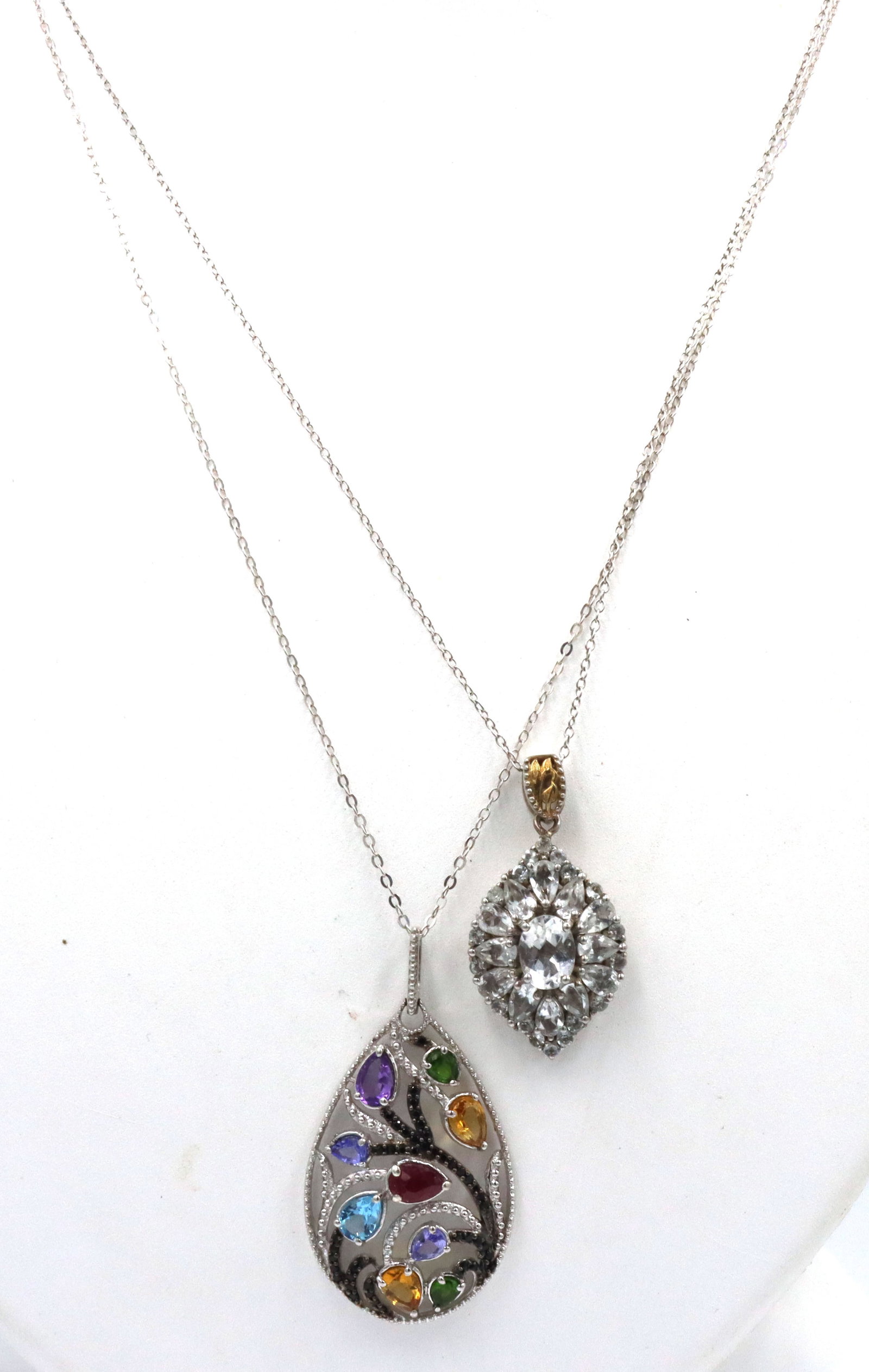 Lot of 2 necklaces in 925 sterling silver: Lot of 2 necklaces in 925 sterling silver. Multi color stone pendant on 20-inch chain necklace and Cubic zirconia pendant on 18-inch chain necklace. The total weight of the lot is 13.1 grams.