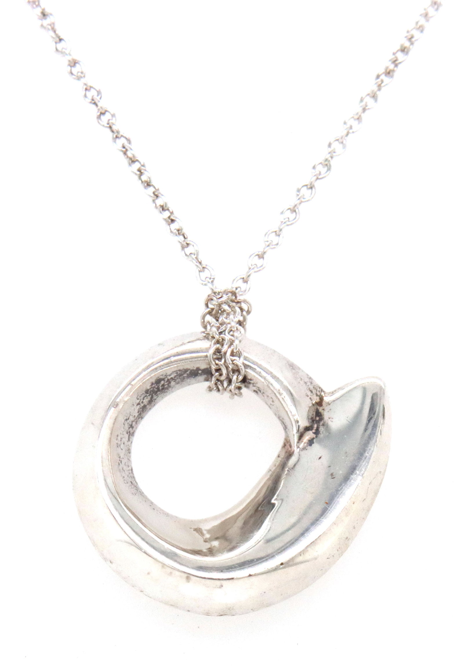 Tiffany & Co Frank Gehry fish circle pendant necklace: 925 Sterling silver Tiffany & Co Frank Gehry fish circle pendant on 15-inch chain necklace. The total weight of the necklace is 5.40 grams.