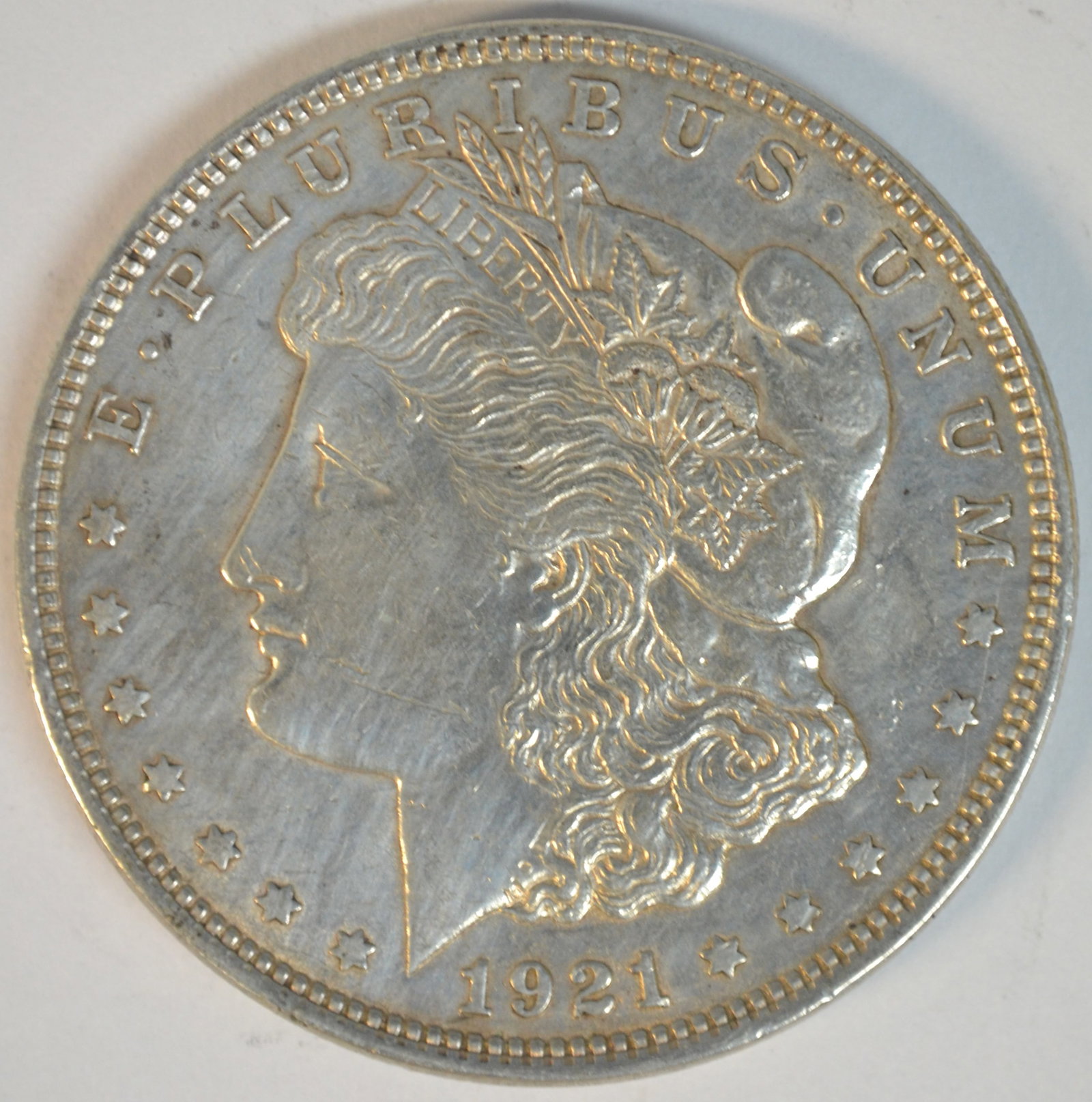 1921 Morgan Silver Dollar Philadelphia Mint Choice About Uncirculated (AU-55): 1921 Morgan Silver Dollar, the final year of issue for the iconic Morgan Dollar series. Struck in 90% silver at the Philadelphia Mint (no mintmark), this historic coin represents the last Morgan Dolla