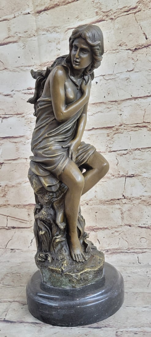 Nude Lady Bronze Statue: The fair maiden can be seen having just finished bathing in the waters of a lake. She is viewed from her right side, leaning on the rocks of a cliff, as she clings to the towel that the sudden gust