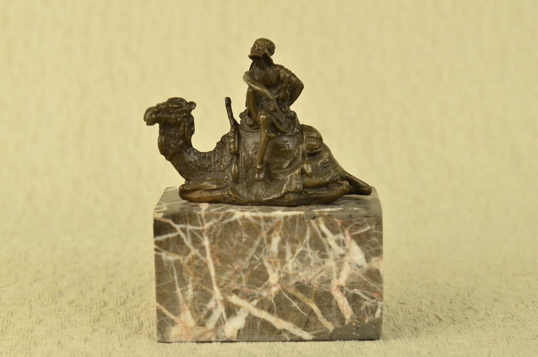 Arab Man Camel Rider Bronze Sculpture: After years of traveling the desert with his faithful camel, the two of them are inseparable. The camel does not mind one bit that his owner is perched on top of him as he takes a rest. The camel is