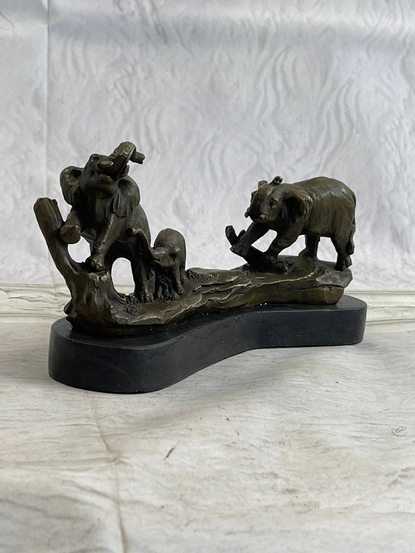 Three Elephants Walking Bronze Statue: Some of the few members of an elephant clan can be imagined on the banks of a watering hole in the hot plains of Africa. Reaching the final destination after an epic migration they all trumpet their t